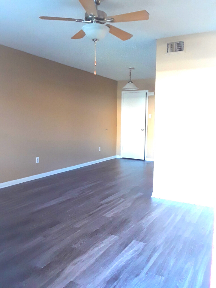 an empty living room with wood floors and a ceiling fan