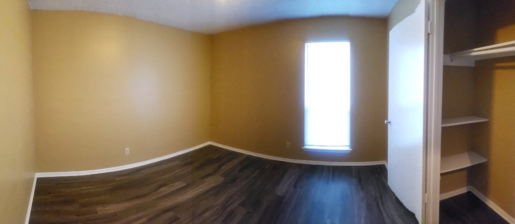 an empty room with a window and wooden floors