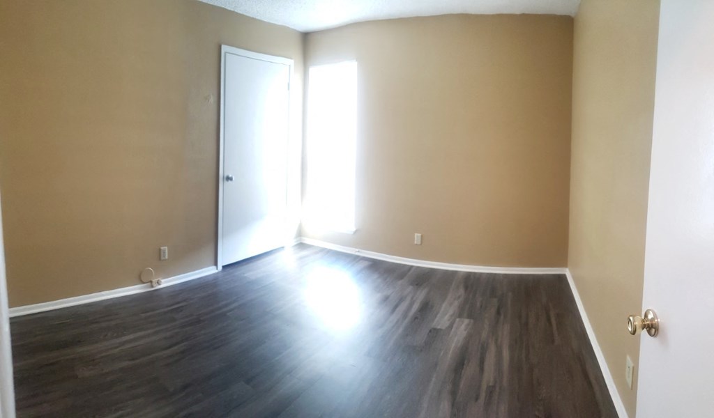 an empty living room with wood floors and a door