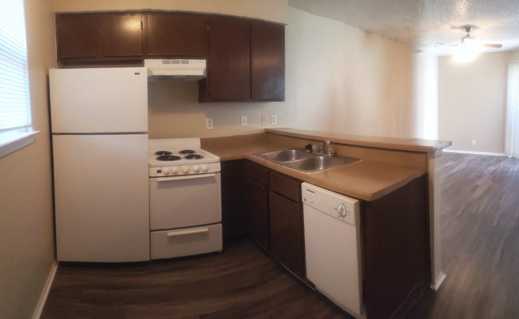 an empty kitchen with white appliances and a sink