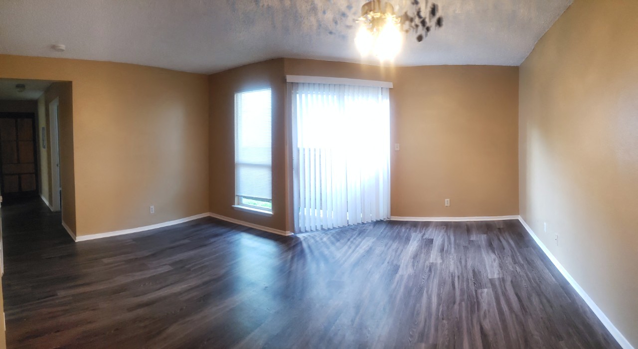 an empty living room with wood floors and a window