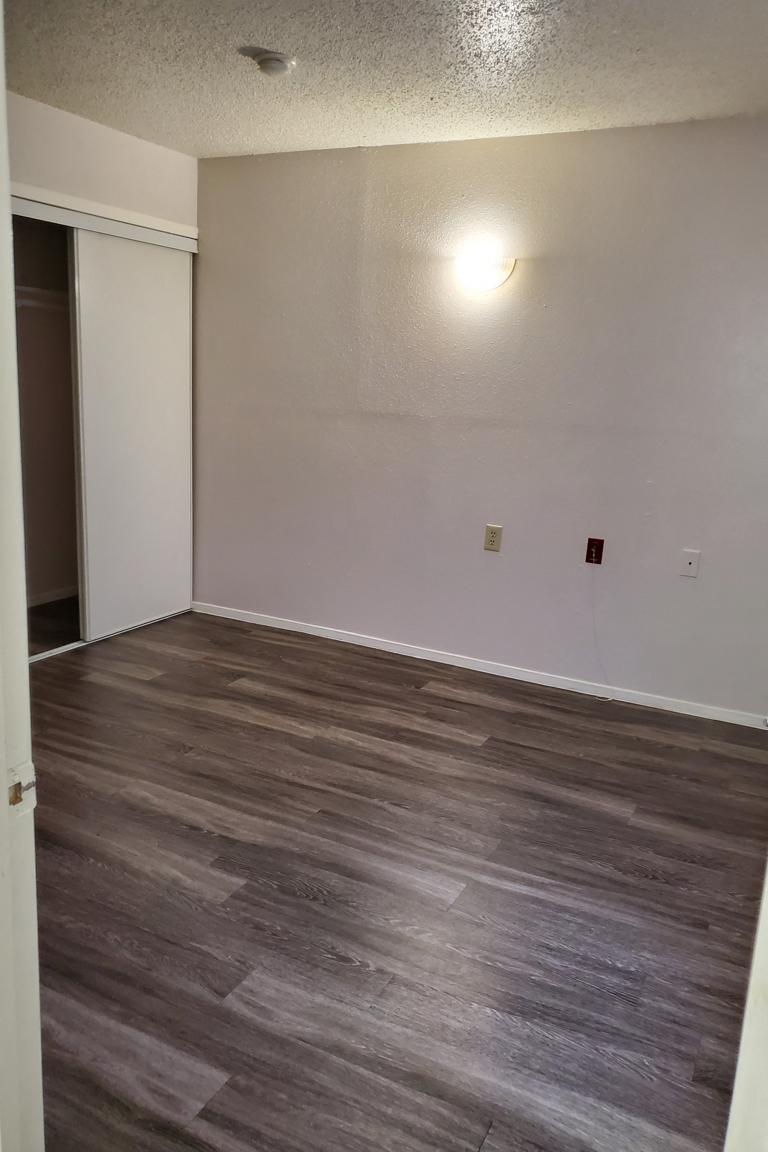 an empty living room with wood flooring and white walls