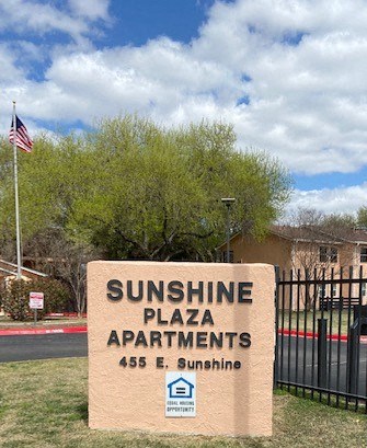 a sunshine plaza apartments sign in front of a gate