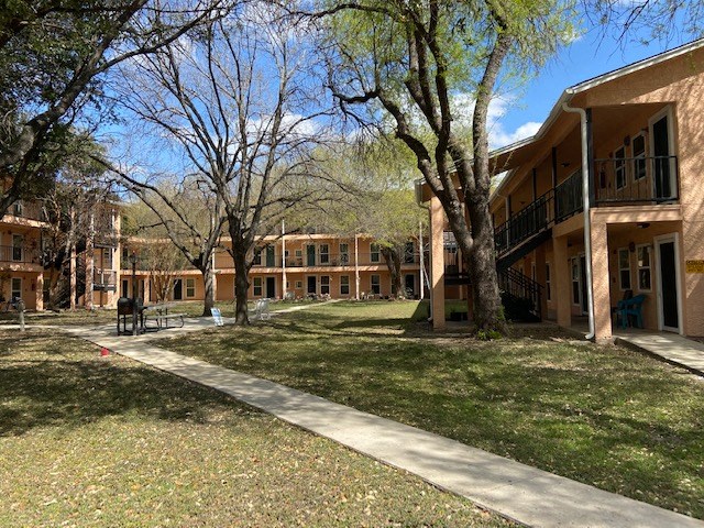 the courtyard of a building with trees and a sidewalk