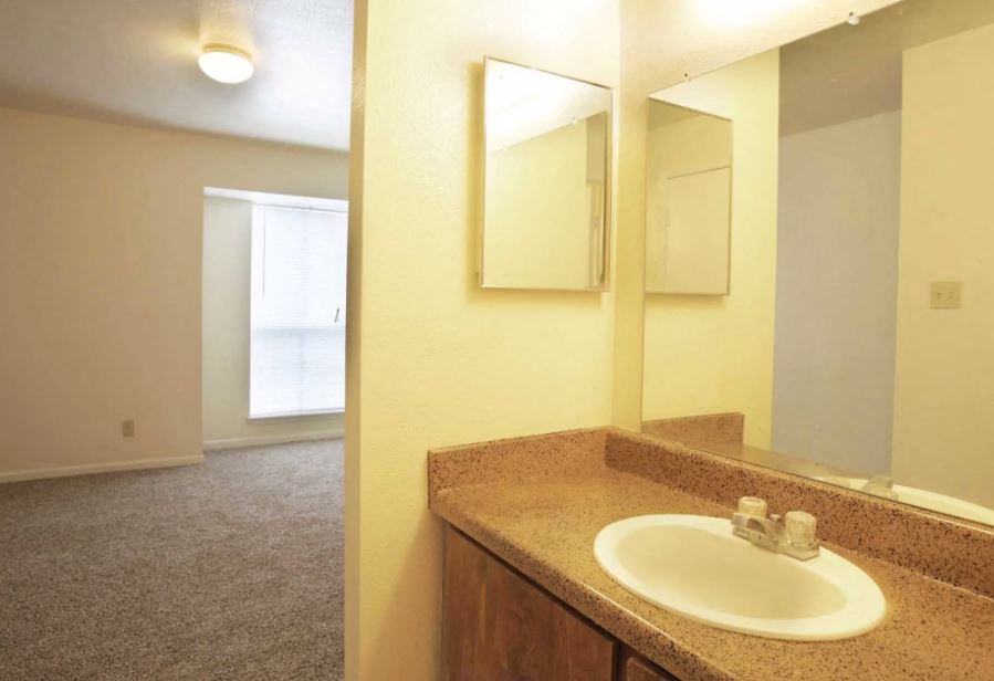 Bathroom sink and mirrored medicine cabinet with partial view of bedroom