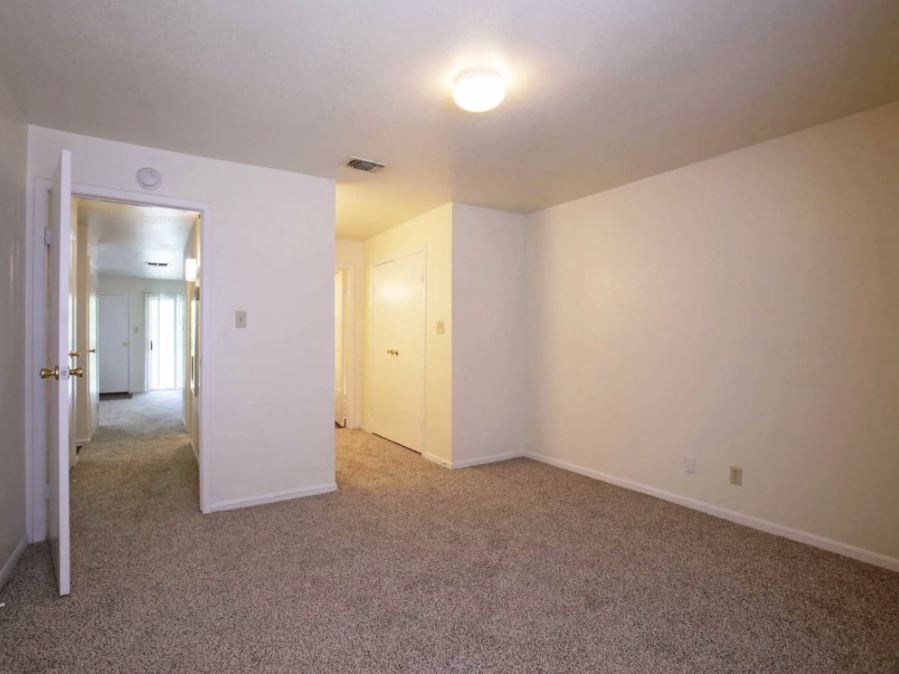 Spacious bedroom with sandy colored carpets and eggshell white walls