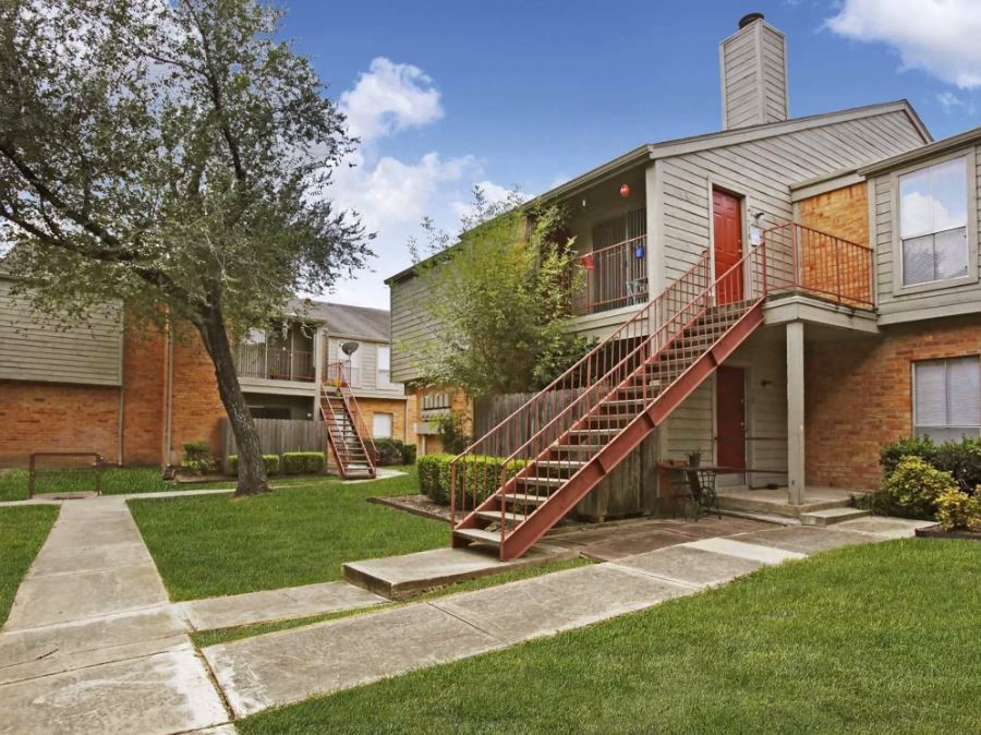 apartment exterior with grey sidewalks and beige and red apartments