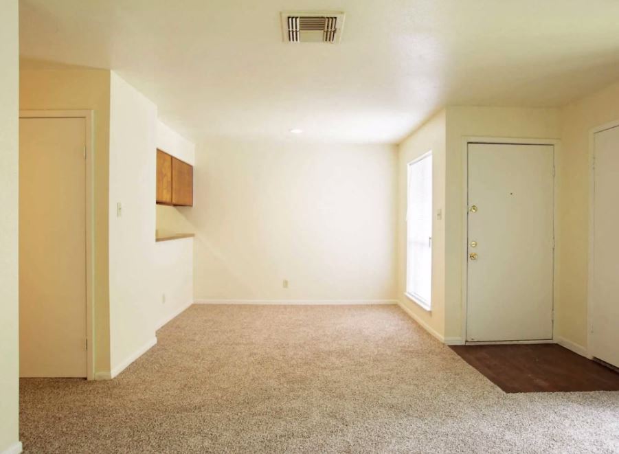 Open living room space with sand colored carpet and eggshell white walls