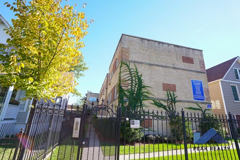 a brick building with a fence and a tree in front of it