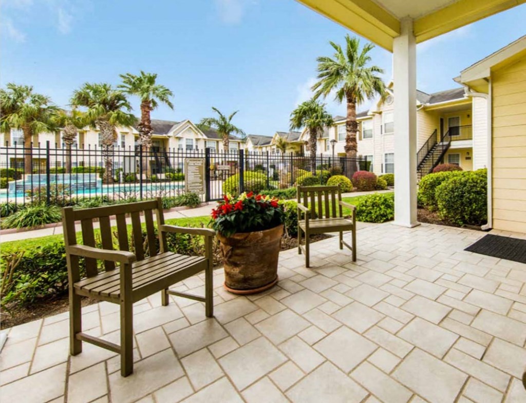 a patio with two benches and a pool in the background