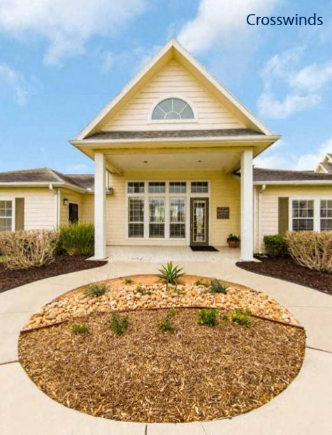 the front of a house with a circle of landscaping in front of it