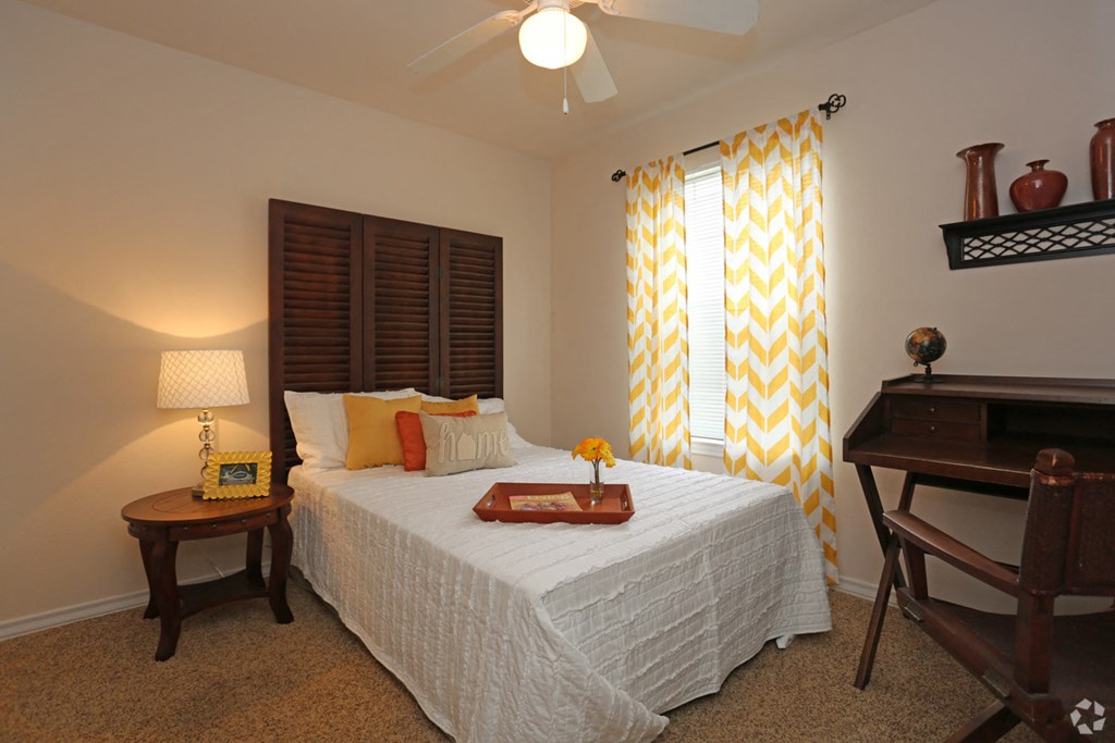 a bedroom with a bed and a desk and a window