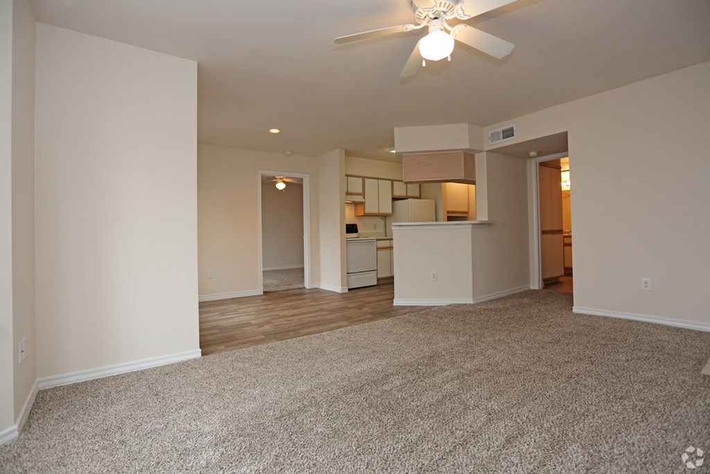 an empty living room and kitchen with a ceiling fan