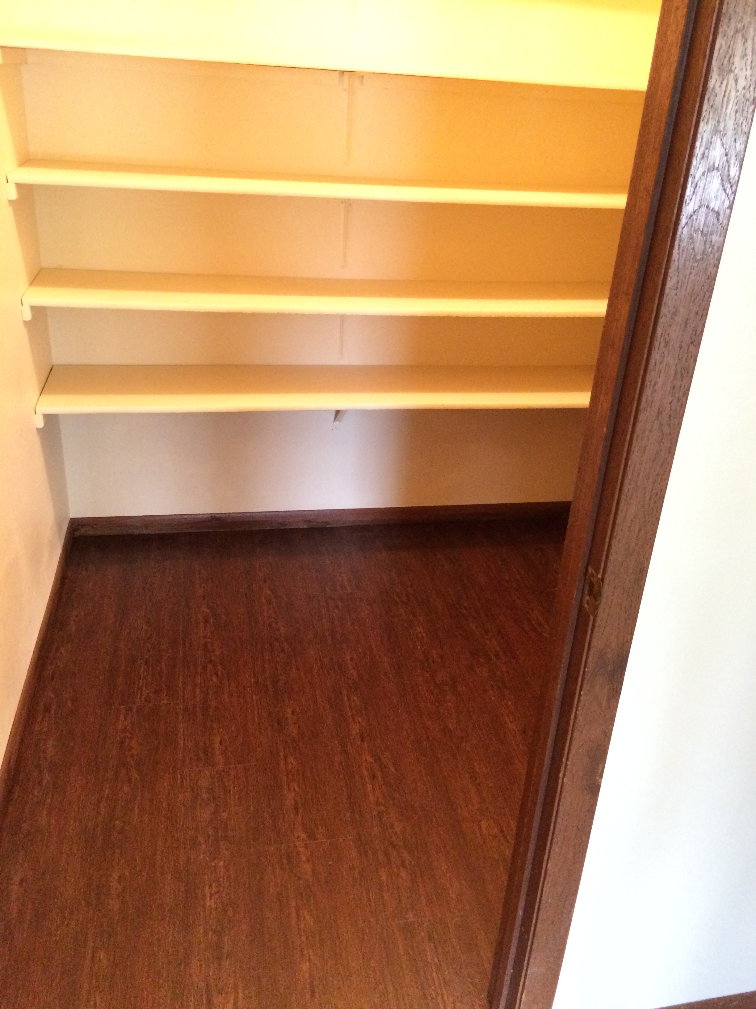 a walk in closet with shelves and a wooden floor