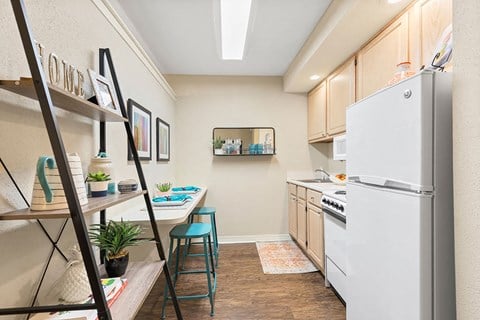 A kitchen with a white refrigerator and a wooden floor.