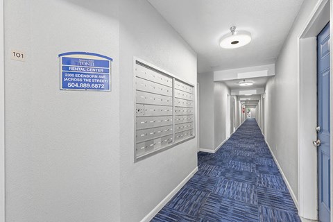 a long hallway with lockers and a blue carpet