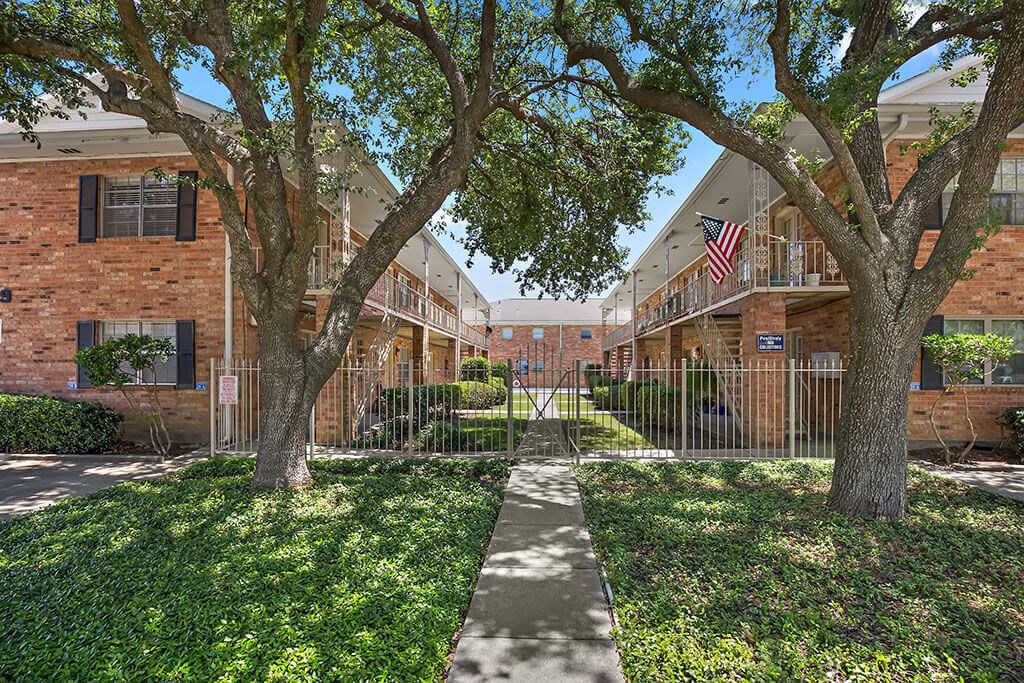 an apartment building with a sidewalk and trees