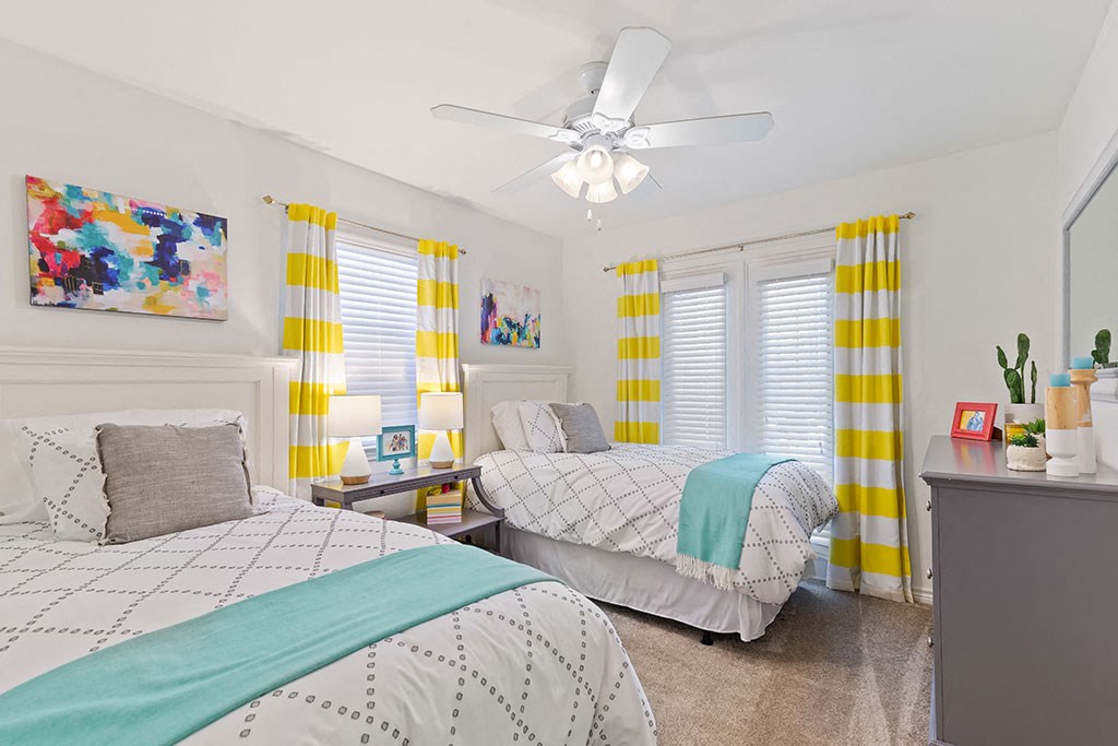 a bedroom with two beds and a ceiling fan