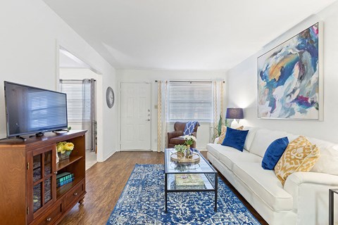 A living room with a white couch, a wooden cabinet, and a painting on the wall.