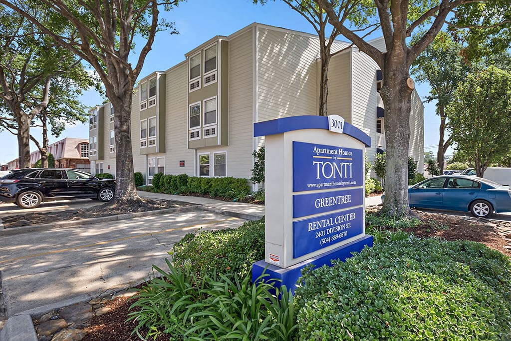 a sign in front of an apartment building with cars parked