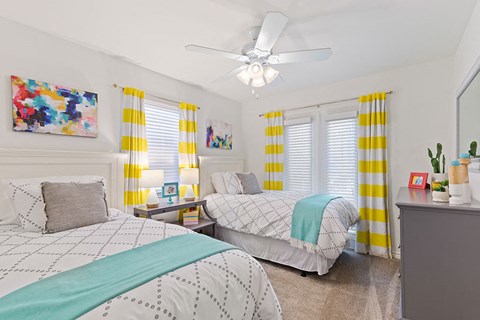 A bedroom with two beds and a ceiling fan.
