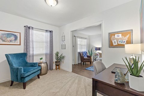A blue chair sits in a living room with a table and a potted plant.