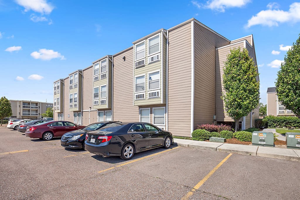 an apartment building with cars parked in a parking lot