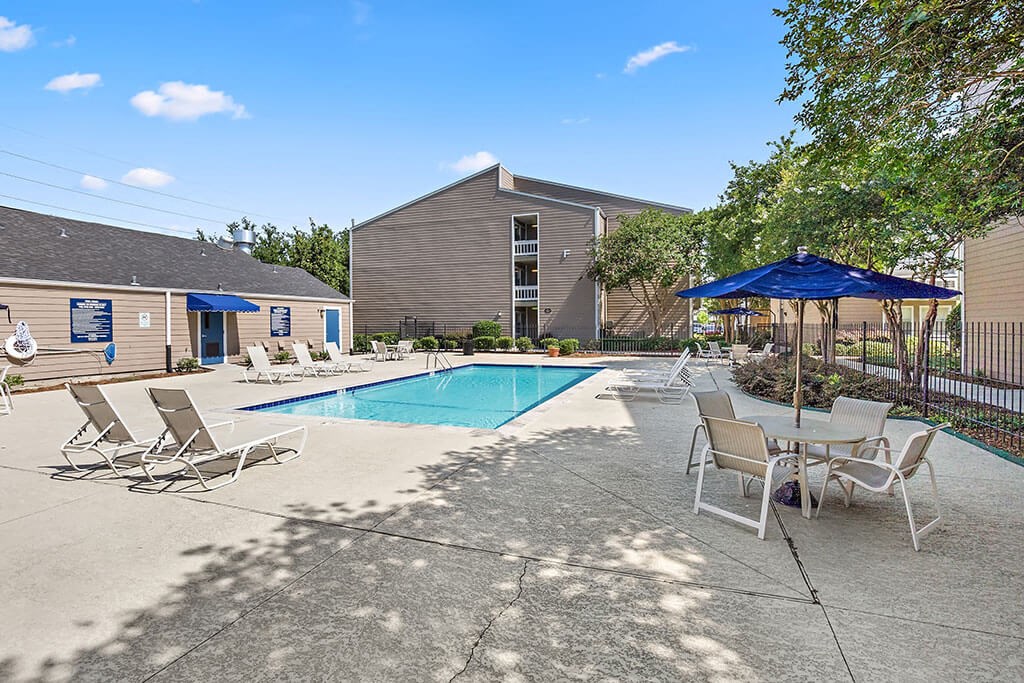 our apartments have a pool and a patio with chairs and umbrellas