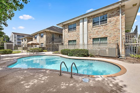 A swimming pool in front of a building with a fence around it.