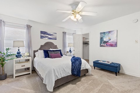 A bedroom with a large bed and a ceiling fan.