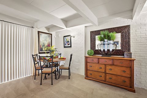 A dining room with a table set for two and a plant on the dresser.