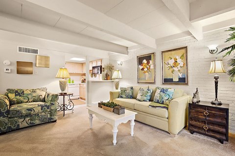 A living room with a white couch and a green patterned chair.