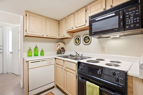 A kitchen with a white stove top oven and a black microwave.