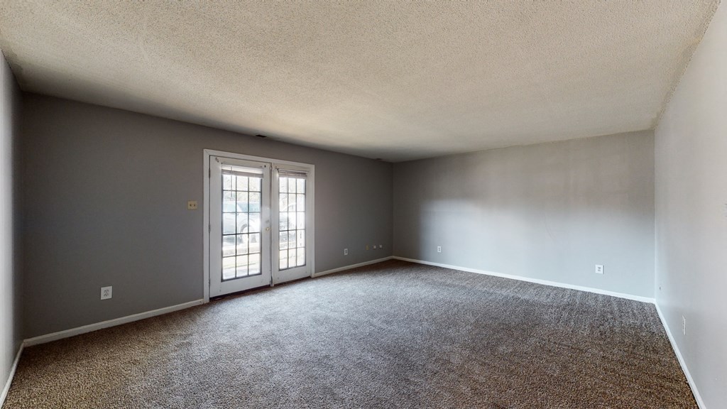 an empty living room with gray walls and white doors
