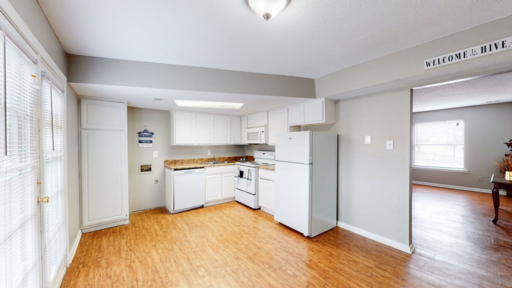 an empty kitchen with white appliances and a wood floor
