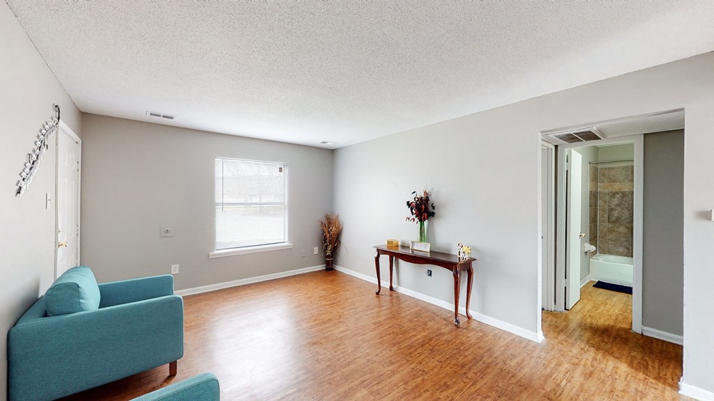 an empty living room with a blue couch and a table