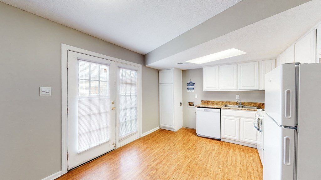 an empty kitchen with white cabinets and a refrigerator