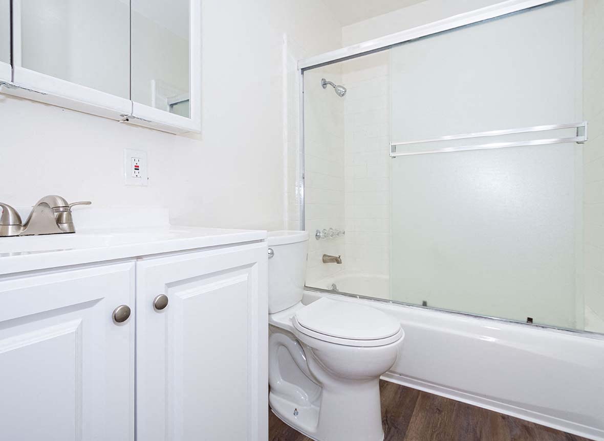 Apartments in San Lorenzo - Bayfair Apartments Bathroom With White Cabinetry, Sliding Door Glass Shower and Tub and Steel Hardware Fixtures