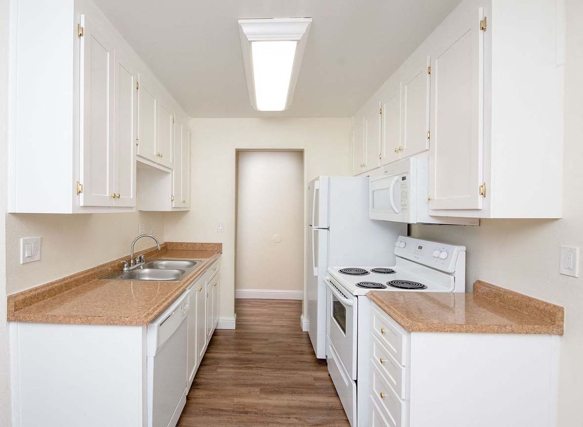 A kitchen with white cabinets and a brown counter top.