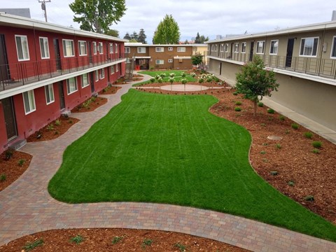 Grass area by buildings l Garden Court Apartments in Alameda, CA