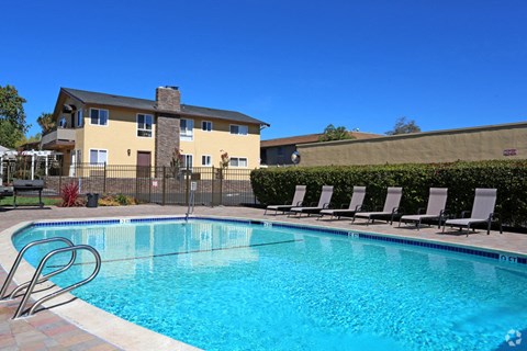 A swimming pool in front of a house with a fence around it.