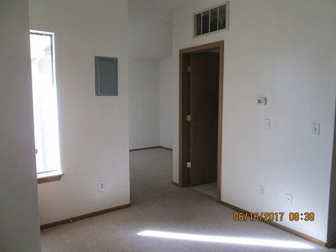 an empty living room with a door to a bedroom