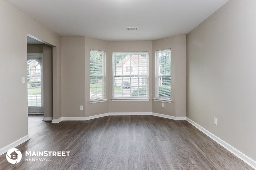 an empty living room with wood flooring and large windows