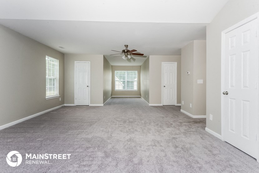 a spacious living room with carpet and a ceiling fan