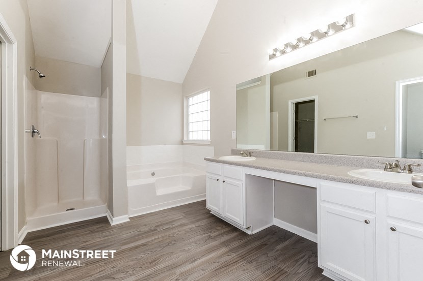 a bathroom with white cabinets and a large mirror and a tub and shower