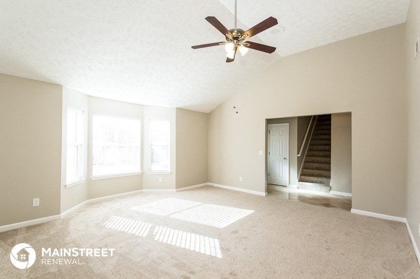 an empty living room with a ceiling fan
