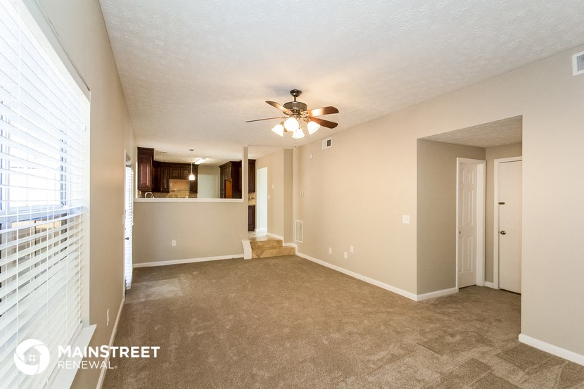 an empty living room with a ceiling fan and a window