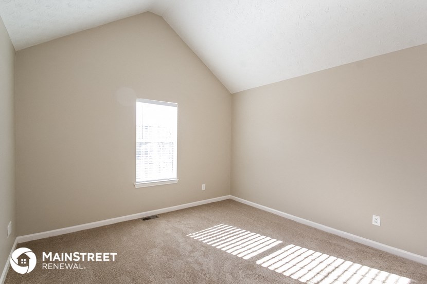 the upstairs bedroom with carpet and a window