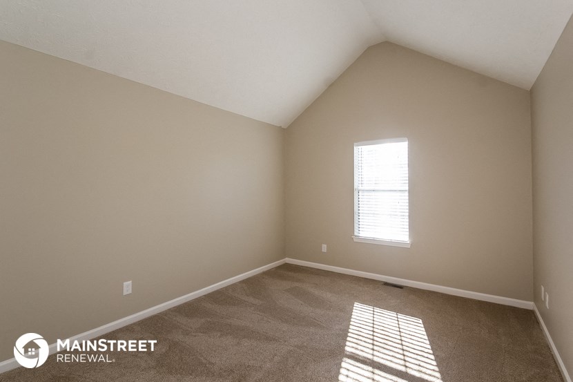 the upstairs bedroom with carpet and window