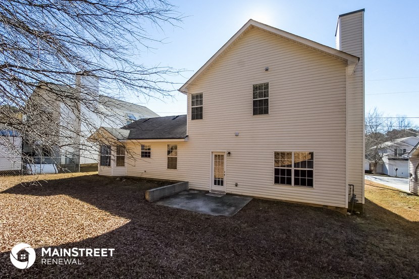 the back of a white house with a gravel yard and a white